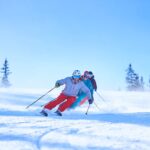 Row of male and female skiers skiing down snow covered ski slope, Aspen, Colorado, USA